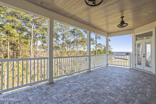 view of patio with ceiling fan, french doors, and a water view