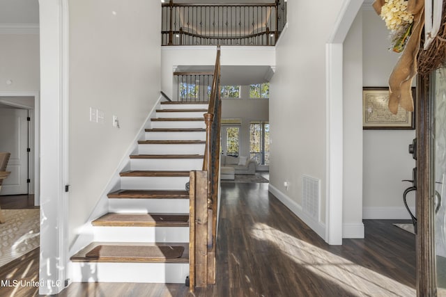 stairs with a high ceiling, hardwood / wood-style flooring, french doors, and crown molding