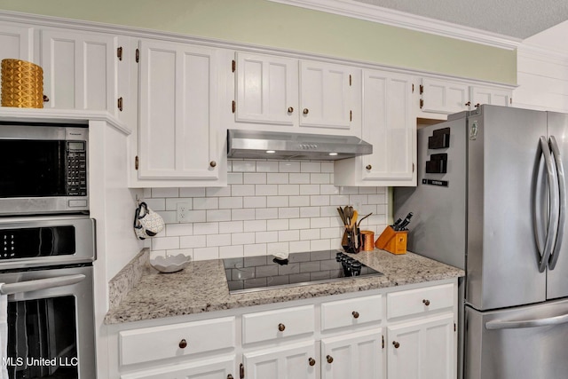 kitchen with white cabinets, range hood, appliances with stainless steel finishes, and tasteful backsplash