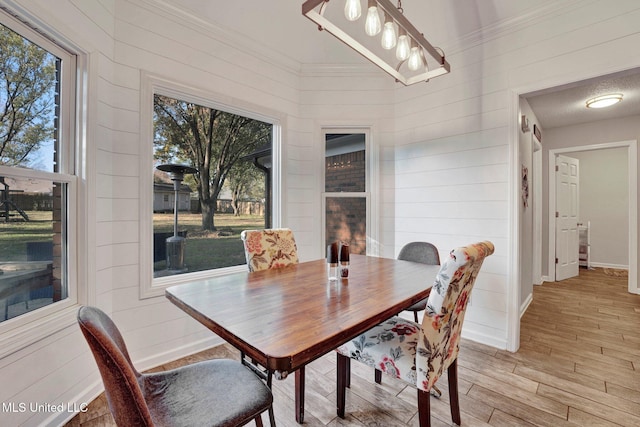 dining area featuring light wood-type flooring, crown molding, and a wealth of natural light