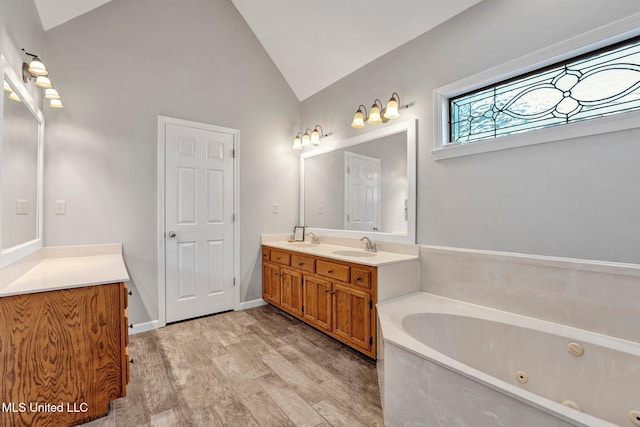 bathroom with hardwood / wood-style floors, vanity, a tub to relax in, and vaulted ceiling