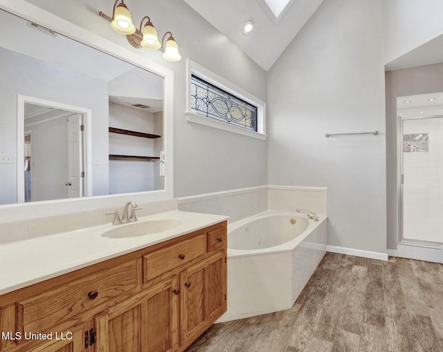 bathroom with vaulted ceiling with skylight, vanity, a bath, and hardwood / wood-style flooring