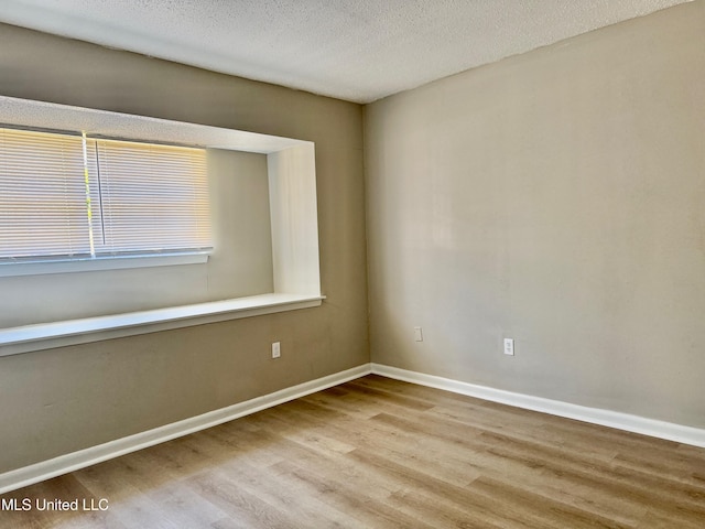 spare room with a textured ceiling and light wood-type flooring