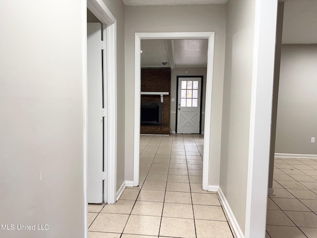 hall with a textured ceiling and light tile patterned flooring