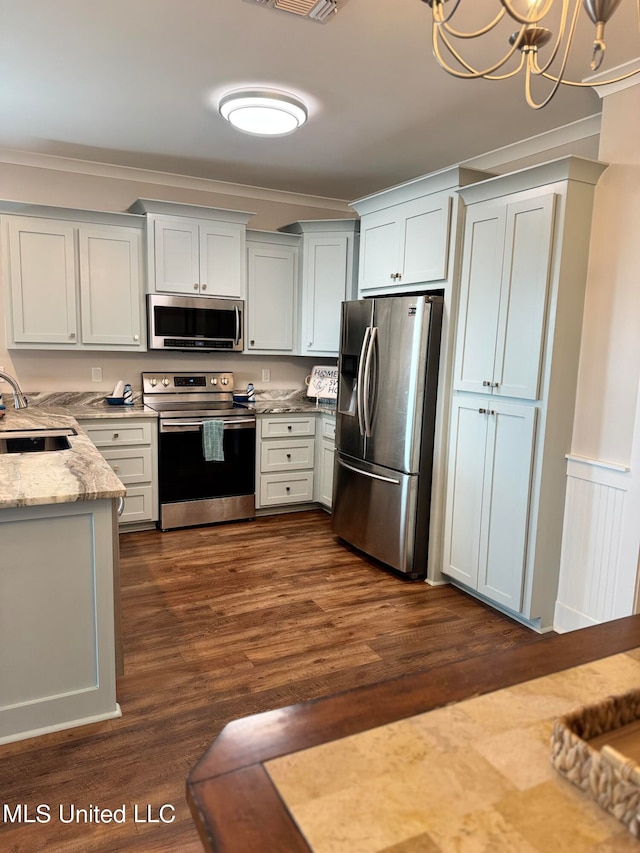 kitchen with dark hardwood / wood-style flooring, stainless steel appliances, sink, pendant lighting, and white cabinetry