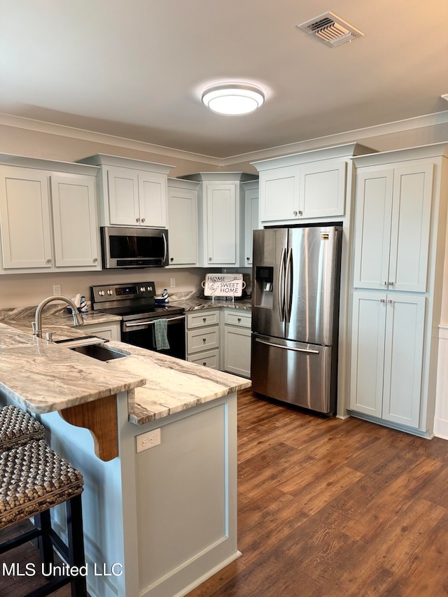 kitchen with light stone countertops, sink, dark wood-type flooring, stainless steel appliances, and a kitchen bar