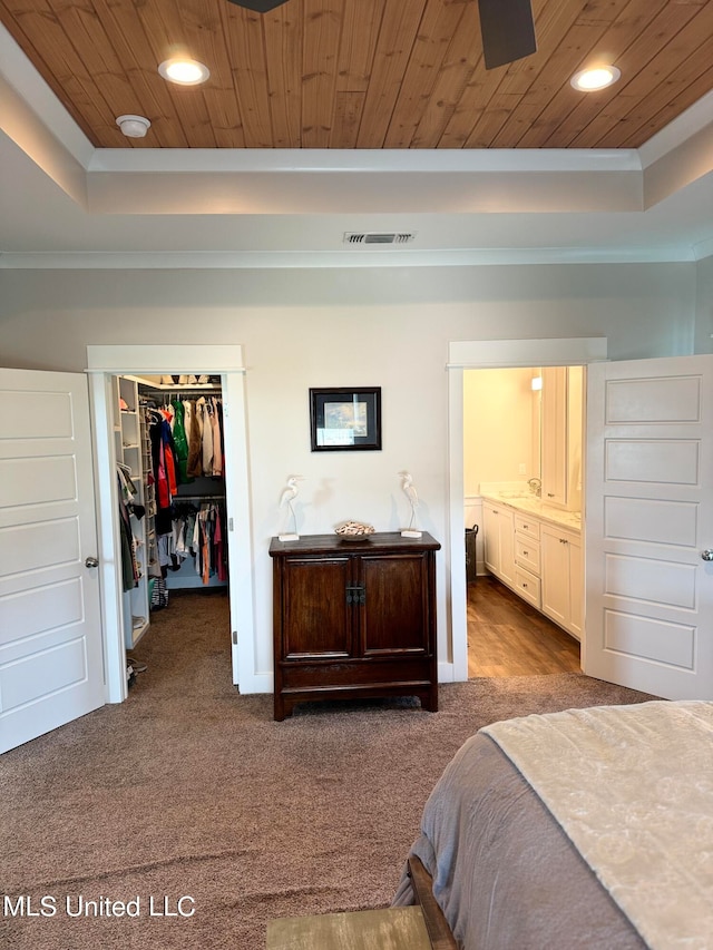 carpeted bedroom featuring a raised ceiling, a closet, ornamental molding, and wood ceiling