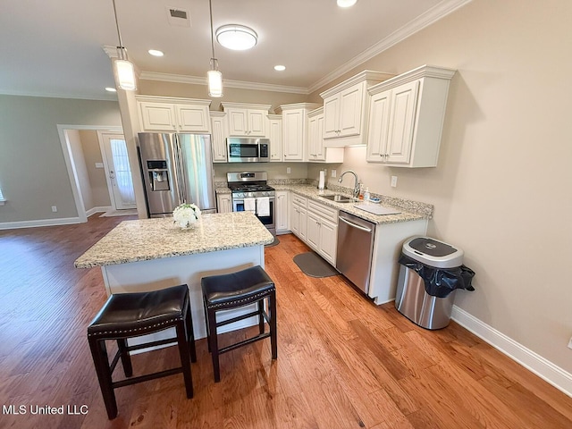 3041 Brambleberry Cv, Southaven, MS 38672 - kitchen with stainless steel appliances, ornamental molding, light wood-type flooring, a center island, and white cabinets