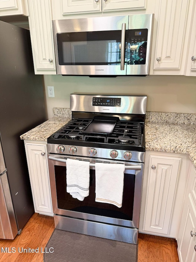 3041 Brambleberry Cv, Southaven, MS 38672 - kitchen featuring stainless steel appliances, light wood-style floors, white cabinets, and light stone counters