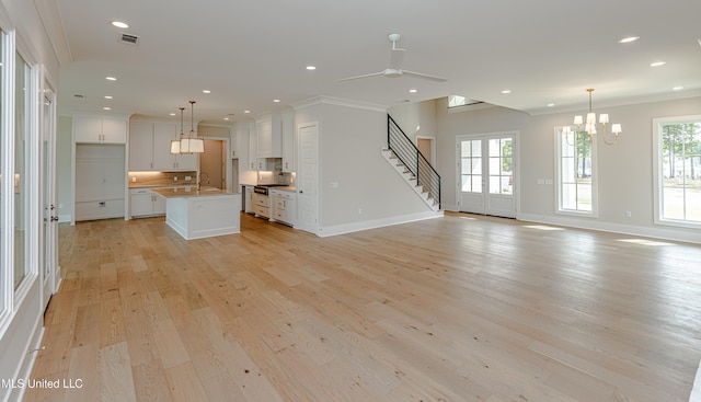 unfurnished living room with ceiling fan with notable chandelier, sink, light hardwood / wood-style flooring, and ornamental molding