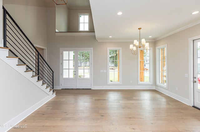 entrance foyer featuring ornamental molding, french doors, a notable chandelier, and light hardwood / wood-style floors