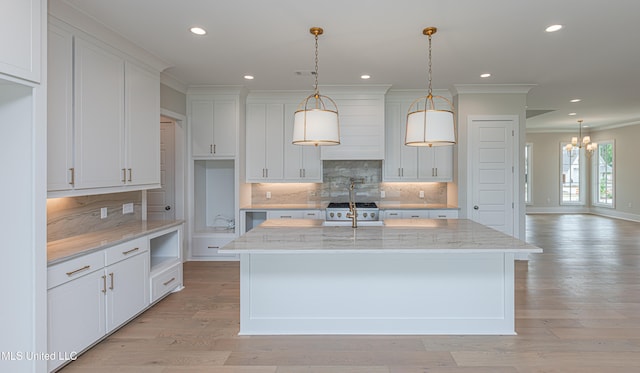 kitchen featuring white cabinets, light hardwood / wood-style floors, a center island with sink, and light stone counters