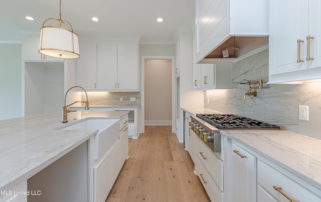 kitchen featuring white cabinets, light wood-type flooring, tasteful backsplash, and pendant lighting