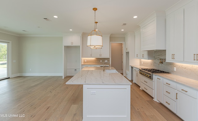 kitchen with stainless steel gas stovetop, sink, light hardwood / wood-style floors, and a kitchen island with sink