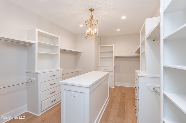 walk in closet featuring light hardwood / wood-style floors and a notable chandelier