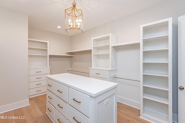 walk in closet with an inviting chandelier and light hardwood / wood-style flooring