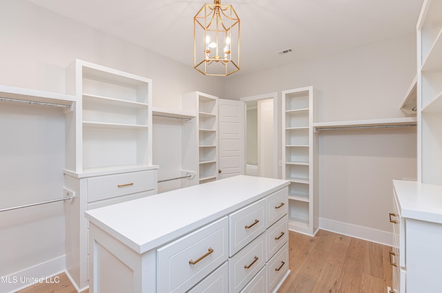 walk in closet with light wood-type flooring and a notable chandelier