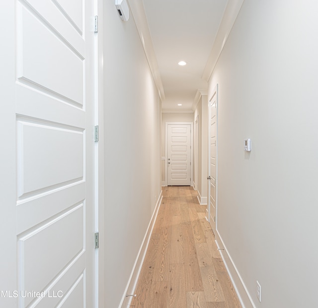 hallway featuring crown molding and light hardwood / wood-style flooring