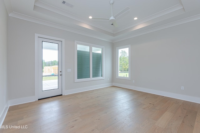 spare room with ceiling fan, a tray ceiling, ornamental molding, and light hardwood / wood-style flooring