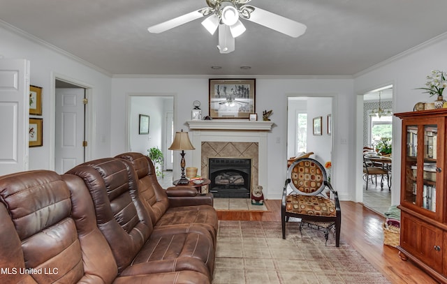 218 Harbor Ln, Brandon, MS 39047 - living room featuring crown molding, a ceiling fan, light wood-style floors, a tile fireplace, and a chandelier