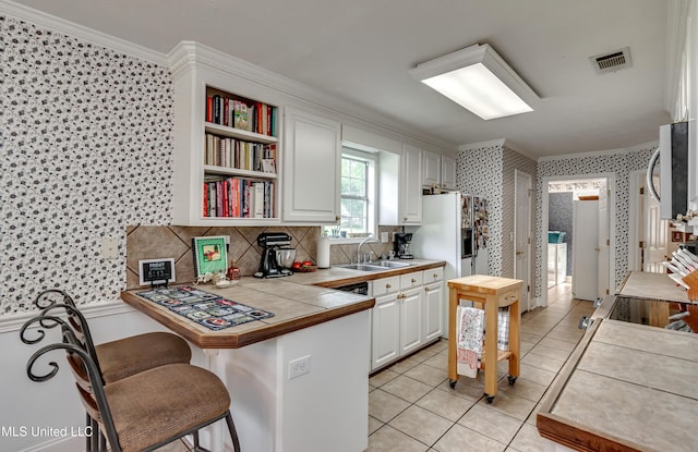 218 Harbor Ln, Brandon, MS 39047 - kitchen with wallpapered walls, a sink, ornamental molding, tile countertops, and a kitchen bar