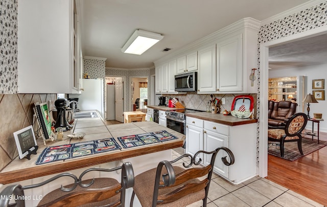 218 Harbor Ln, Brandon, MS 39047 - kitchen featuring appliances with stainless steel finishes, white cabinets, tile countertops, a sink, and crown molding