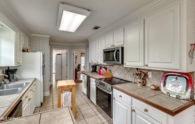 218 Harbor Ln, Brandon, MS 39047 - kitchen with appliances with stainless steel finishes, ornamental molding, white cabinets, tasteful backsplash, and a sink