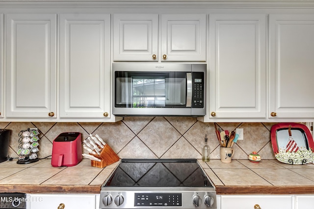 218 Harbor Ln, Brandon, MS 39047 - kitchen with stainless steel appliances, white cabinetry, and decorative backsplash