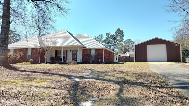 view of front of house featuring covered porch, metal roof, aphalt driveway, and brick siding