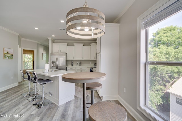 183 Mcdonnell Ave Unit 305, Biloxi, MS 39531 - kitchen with stainless steel fridge with ice dispenser, light wood-style floors, crown molding, white cabinets, and light countertops