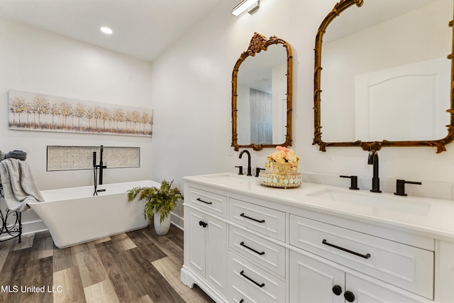 bathroom with vanity, hardwood / wood-style floors, and a bath