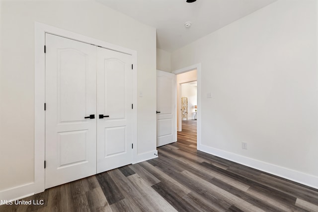 unfurnished bedroom with dark wood-type flooring and a closet