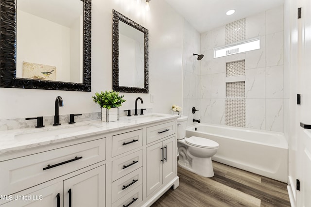 full bathroom with vanity, hardwood / wood-style floors, tiled shower / bath combo, and toilet