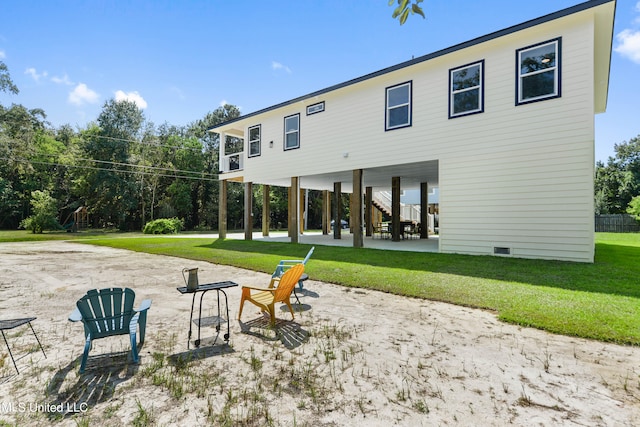 back of house featuring an outdoor fire pit, a patio area, and a lawn