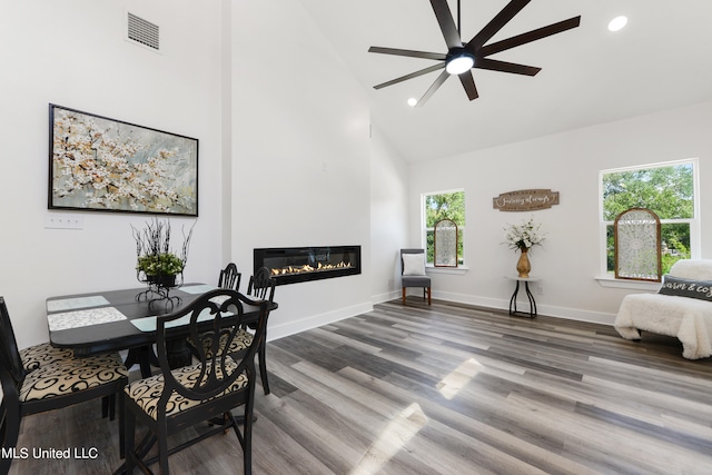 dining area with ceiling fan, high vaulted ceiling, and wood-type flooring