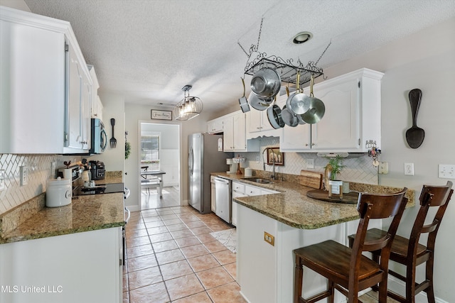9948 Victor Dr, Olive Branch, MS 38654 - kitchen with appliances with stainless steel finishes, a peninsula, tasteful backsplash, a sink, and white cabinets