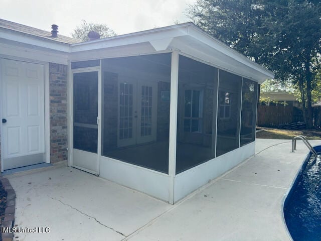 view of side of home with a fenced in pool, a sunroom, and a patio