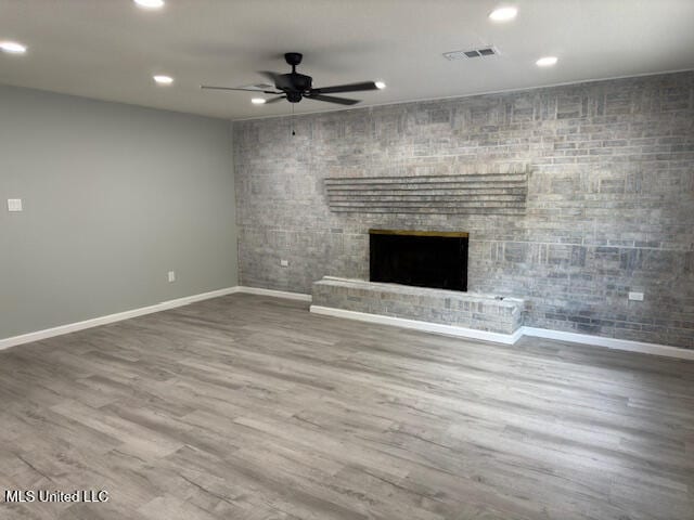 unfurnished living room with a fireplace, wood-type flooring, and ceiling fan