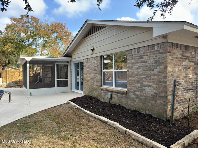 view of property exterior with a patio and a sunroom