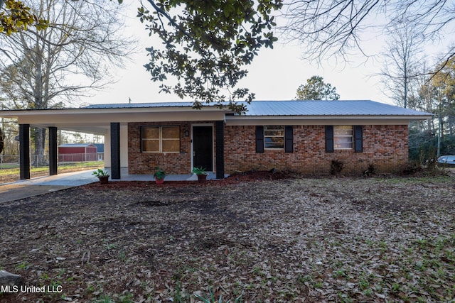 ranch-style home with metal roof, concrete driveway, an attached carport, and brick siding