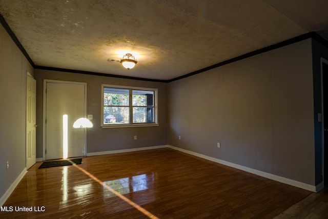 empty room featuring ornamental molding, wood finished floors, and baseboards