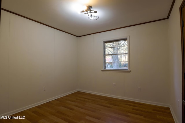 unfurnished room featuring ornamental molding, wood finished floors, and baseboards