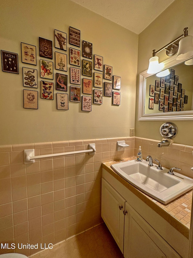 bathroom with tile walls, vanity, a textured ceiling, and tile patterned flooring