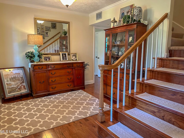 stairway featuring hardwood / wood-style floors, crown molding, and a textured ceiling