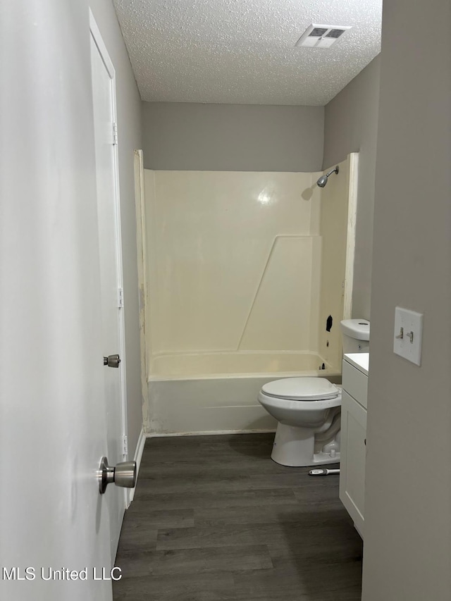 full bathroom with hardwood / wood-style flooring, vanity, toilet, and a textured ceiling