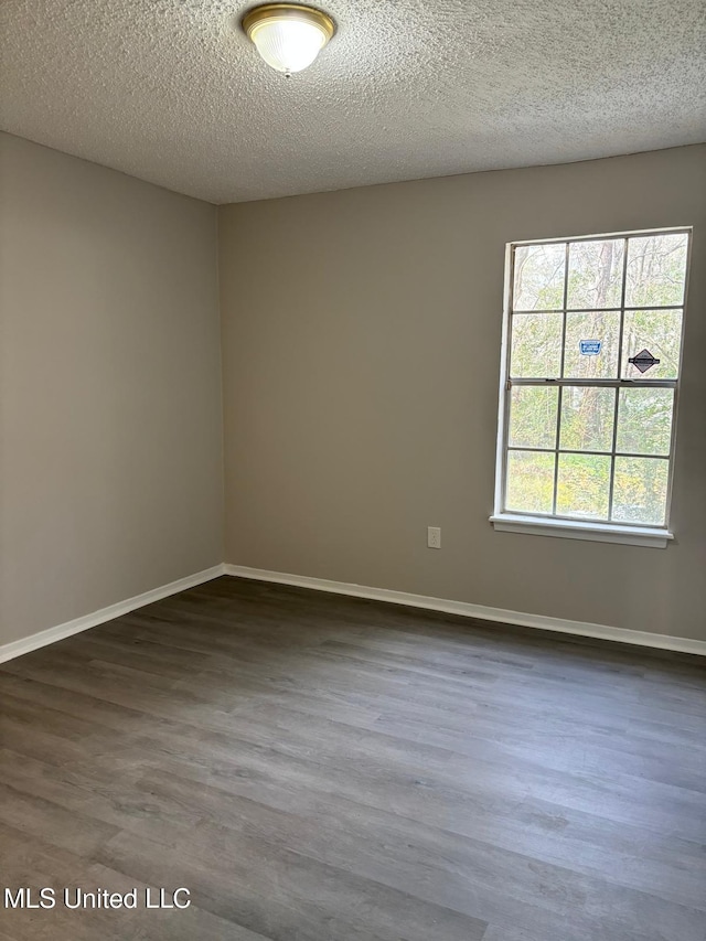 unfurnished room featuring plenty of natural light, a textured ceiling, and dark hardwood / wood-style flooring