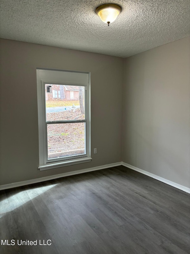 empty room featuring dark hardwood / wood-style flooring and a textured ceiling