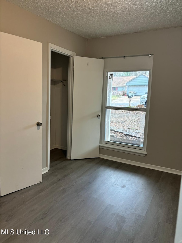 unfurnished bedroom with dark wood-type flooring, a closet, and a textured ceiling