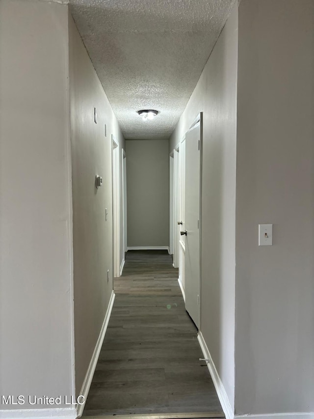 hallway with dark hardwood / wood-style flooring and a textured ceiling