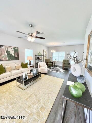 living room featuring vaulted ceiling, hardwood / wood-style floors, and ceiling fan with notable chandelier